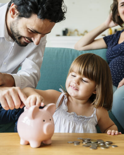 Familie mit Kind spart Geld in einem Sparschwein