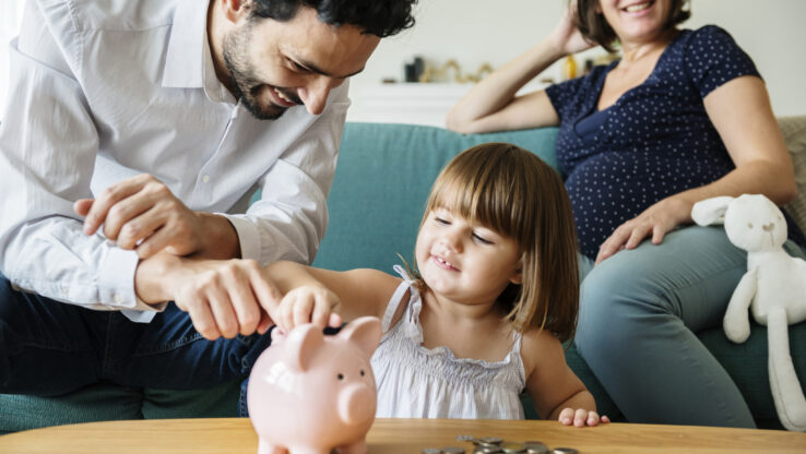 Familie mit Kind spart Geld in einem Sparschwein