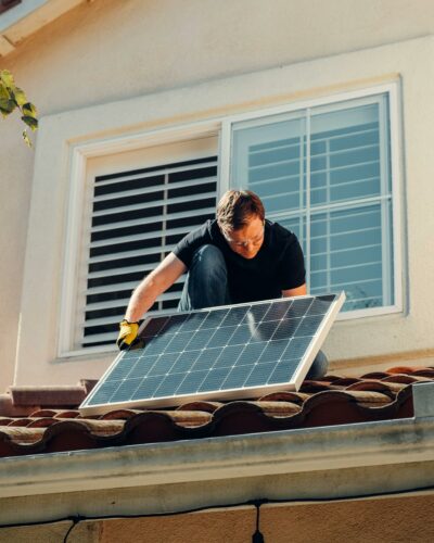 Mann bringt auf dem Hausdach eine Photovoltaikanlage an