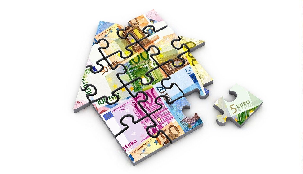 Puzzle in Form eines Hauses. Auf dem Puzzle ist Geld zu sehen.